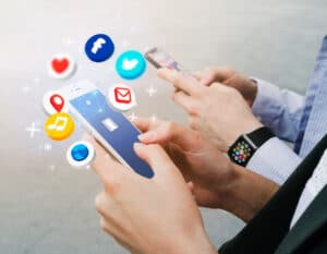 Hands holding smartphones with social media icons, illustrating automated social media management and engagement strategies for businesses.