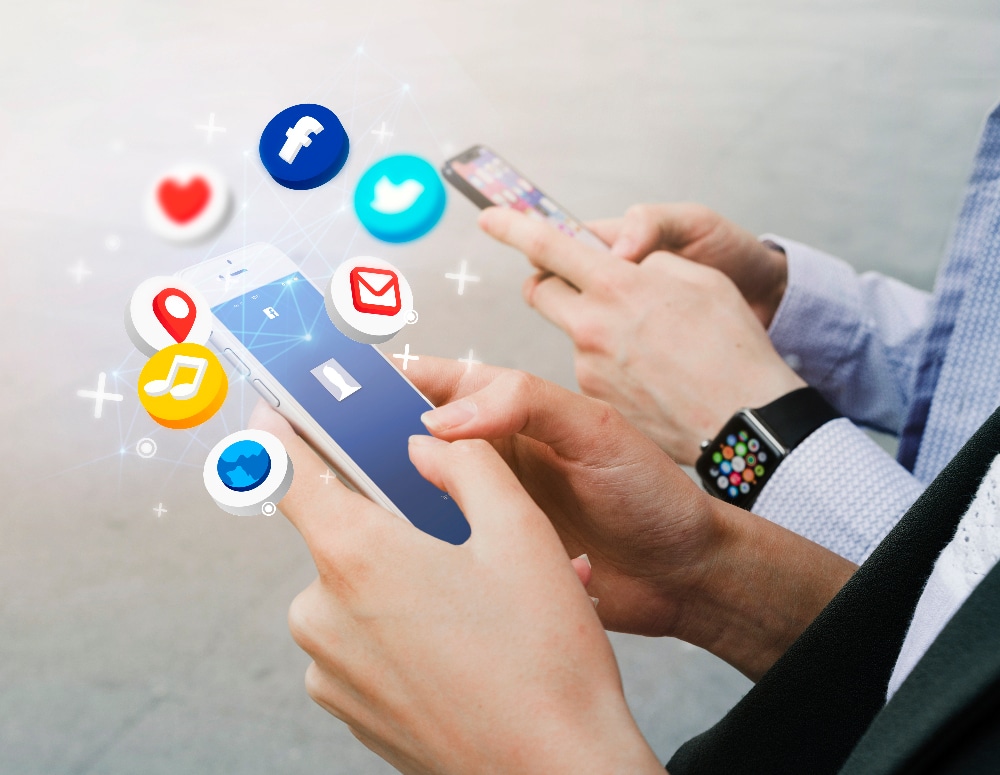 Hands holding smartphones with social media icons, illustrating automated social media management and customer engagement strategies.